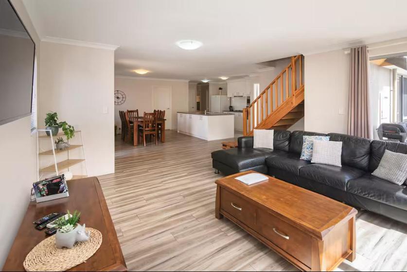 a living room with a black couch and a table at Marina Family Beachscape in Geographe