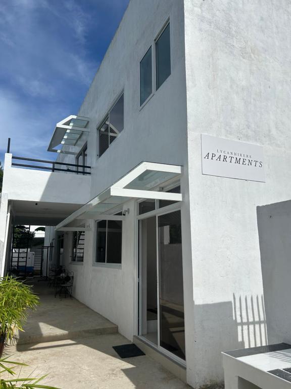 Un edificio blanco con un cartel al costado. en Lycanhikers Apartments, en Panglao