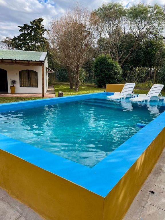 a swimming pool with chairs and a house at Rincón del Sauce in Parana