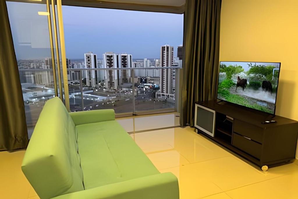 a living room with a green couch and a flat screen tv at Apt Luxo VI no Shopping Df Plaza in Brasilia