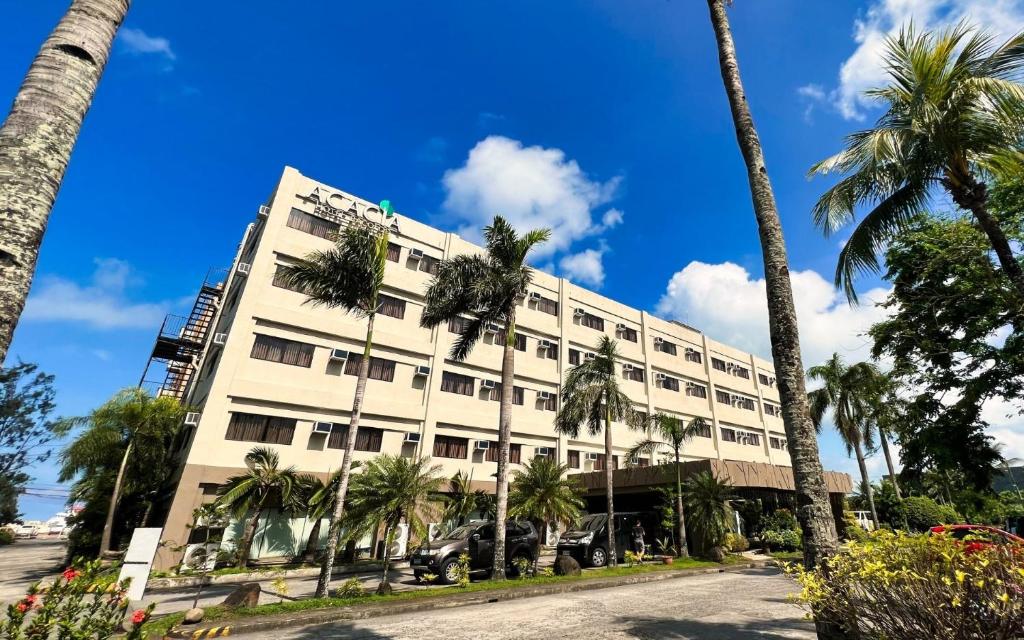 Un gran edificio con palmeras delante. en Acacia Hotel Bacolod, en Bacolod