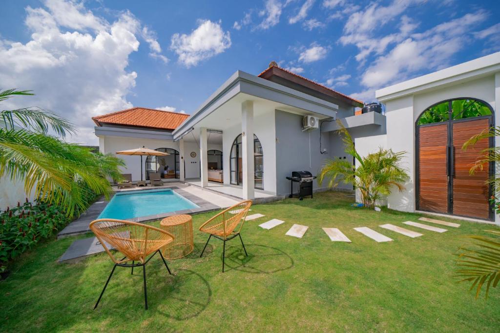 un patio trasero con piscina, 2 sillas y una casa en Villa Intisar - luxury oasis in Canggu, en Canggu