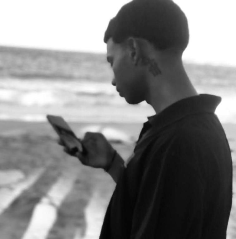 a man looking at his cell phone on the beach at Yeiko in Carlos Guerra
