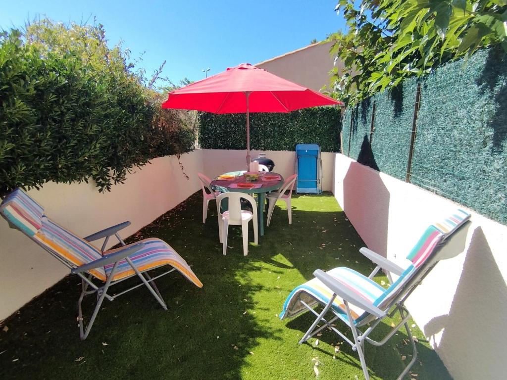 un patio avec une table, des chaises et un parasol dans l'établissement Pavillon Studio - Clim - Proche Plage - Jardin et Parking - 4 Pers - Narbonne Plage - FR-1-795-39, à Narbonne