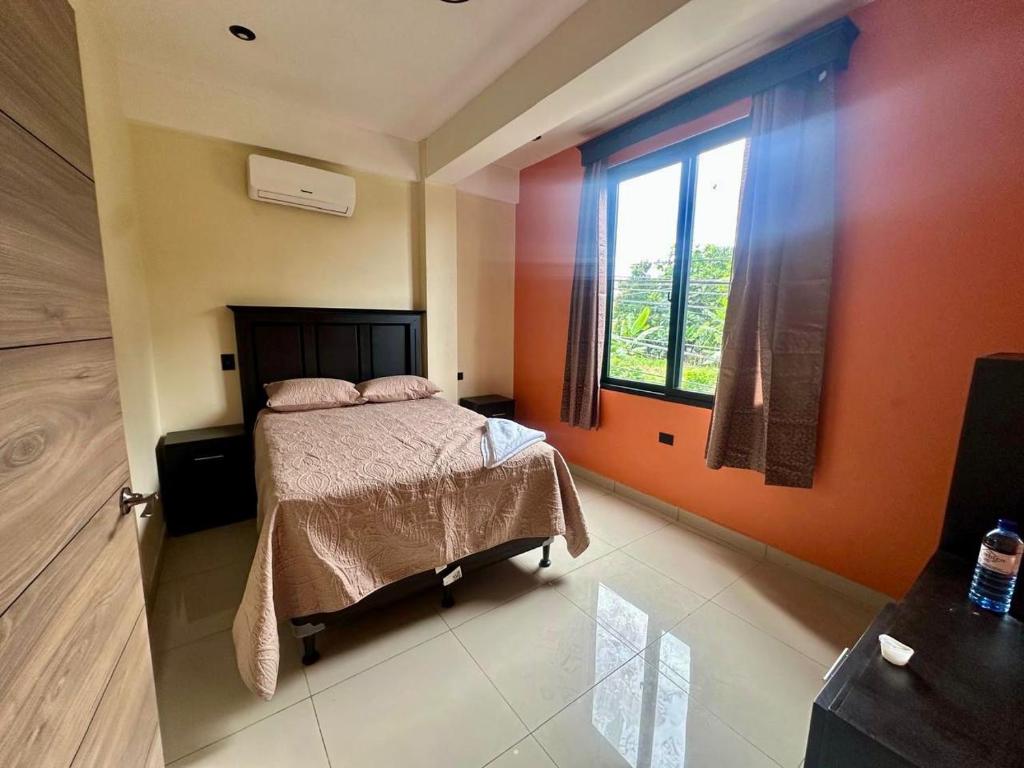 a bedroom with a bed and a large window at Hotel San Isidro in Malacatán