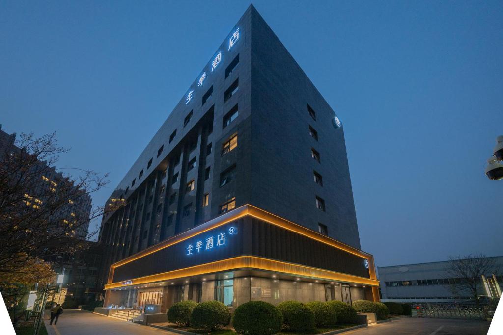 ein hohes Gebäude mit einem Schild an der Seite in der Unterkunft 全季北京亦庄荣华南路酒店 in Peking