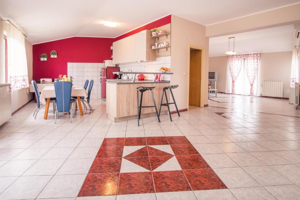 a kitchen and dining room with a red wall at Apartments & Rooms Iva in Vrbnik