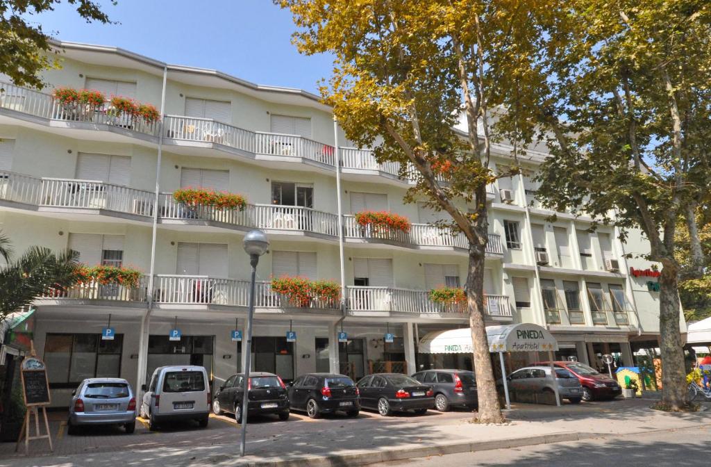 un gran edificio blanco con coches estacionados frente a él en Aparthotel Pineda en Bibione