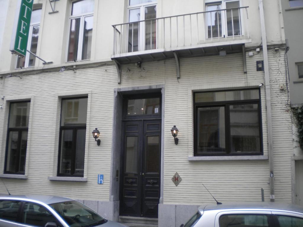 un edificio con una puerta negra y coches aparcados fuera en Hotel Queen Mary, en Bruselas