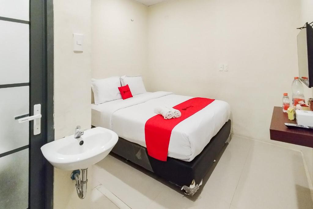 a white bedroom with a bed and a sink at RedDoorz at Rejoss Lux Medan in Medan