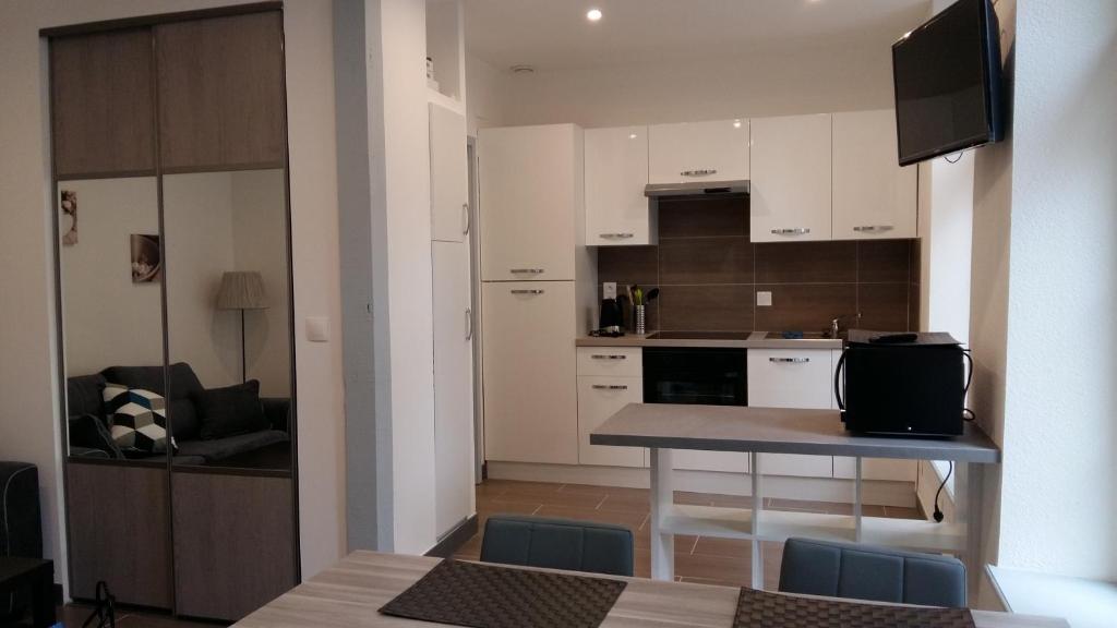 una cocina con armarios blancos y una mesa con sillas. en Tripiers Duplex, en Colmar