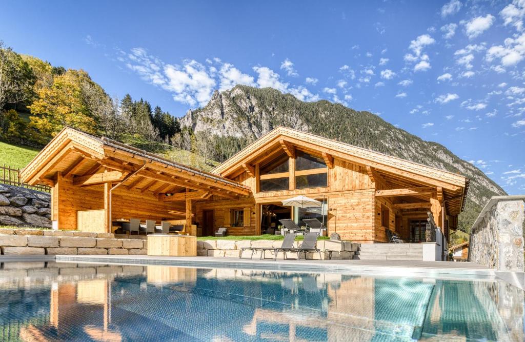 a log home with a pool and a mountain at Penthouse im Chalet GM by A-Appartments in Gallaverda