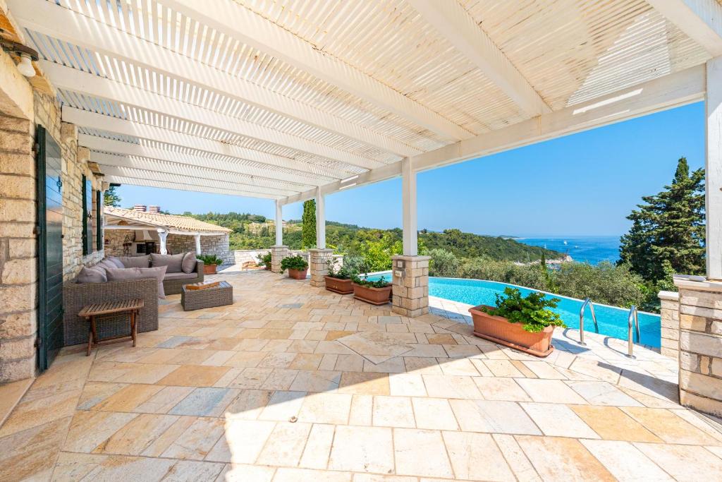 an outdoor patio with a pergola and a pool at Villa Iremia Antipaxos in Antípaxos