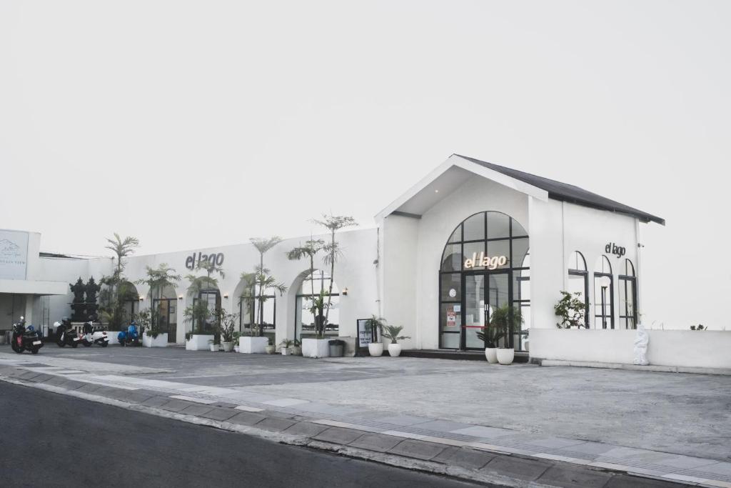 a white building with palm trees in a parking lot at El Lago Hotel in Kintamani