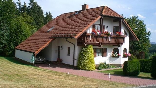 a small house with a balcony with flowers on it at Ferienwohnung Fichtelwald in Fichtelberg