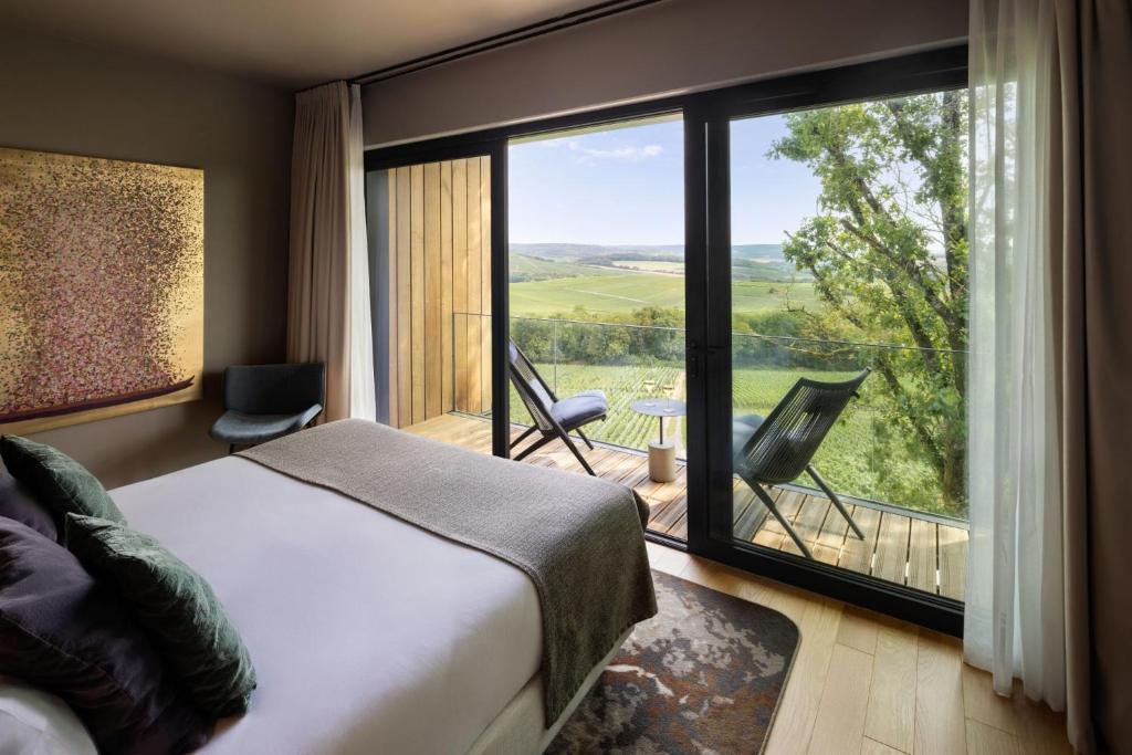a bedroom with a bed and a large window at LOISIUM Wine & Spa Hotel Champagne in Mutigny
