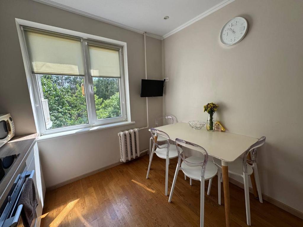a dining room with a table and chairs and a clock at Сучасний комфорт та затишок Південне, Южне in Sychavka