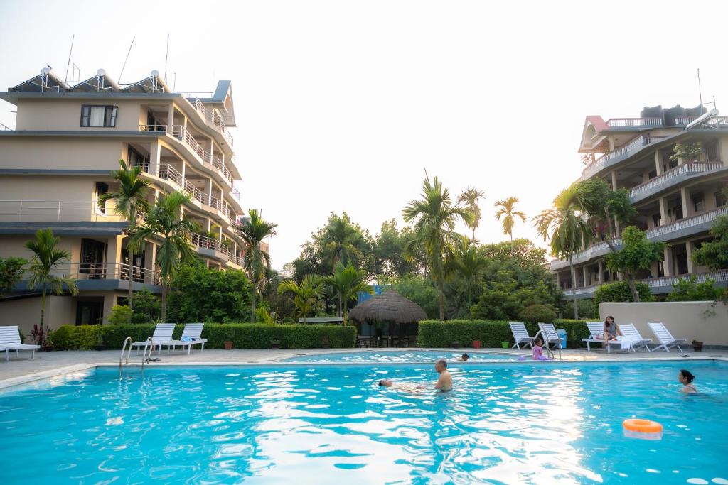 a swimming pool in front of a building with people in it at Hotel Monalisa Chitwan in Sauraha