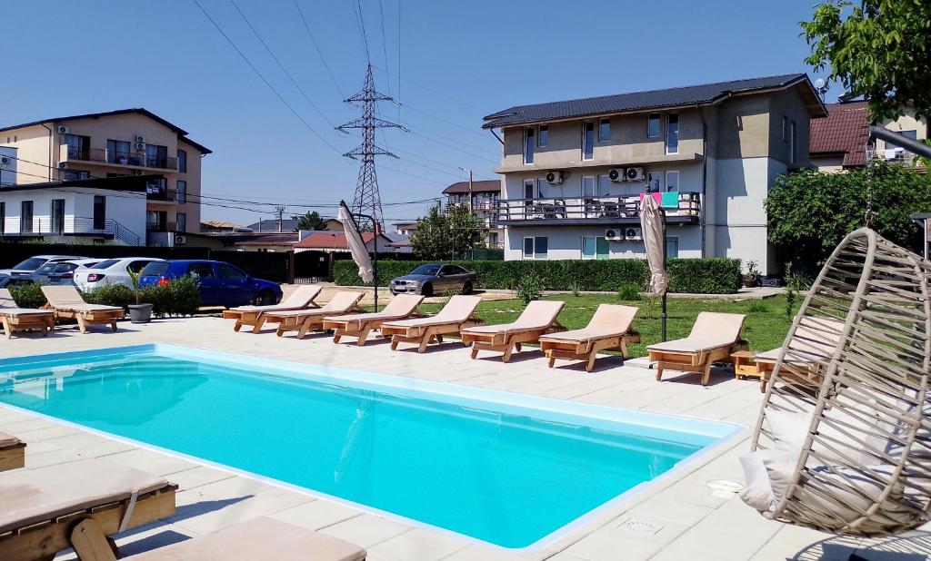 a swimming pool with chaise lounges and chairs next to a building at Vila Atipic in Costinesti