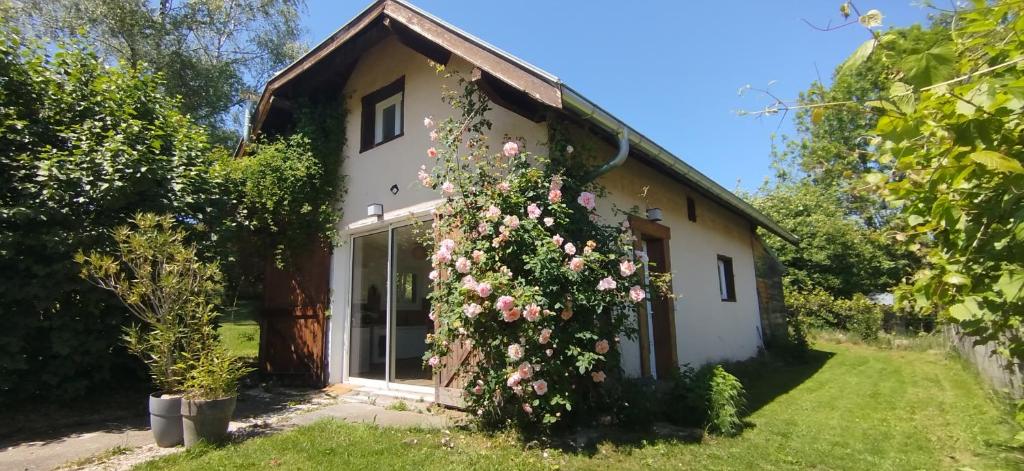 a cottage with a large window and flowers at Maison pleine nature Aiguebellette et Bourget in Loisieux