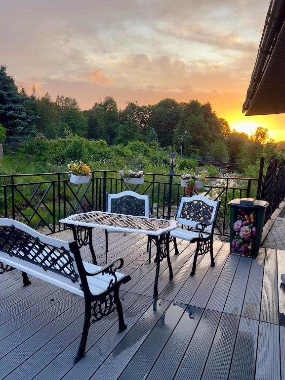 a table and two chairs on a deck with the sunset at Apartamenty Anielski Sen 3 in Świeradów-Zdrój