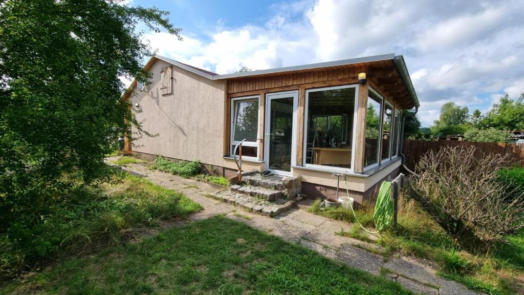 a small house with a large window in a yard at Bungalow Helga in Fürstenwalde