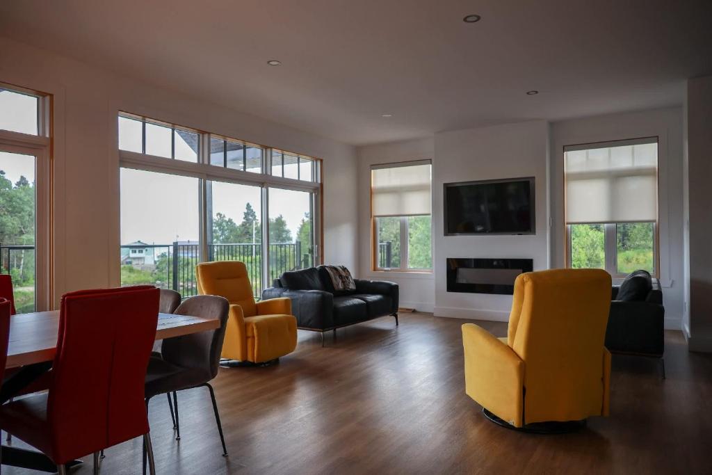 a living room with a table and yellow chairs at Entre lac et Fleuve - Nature & Comfort in Saint-Siméon