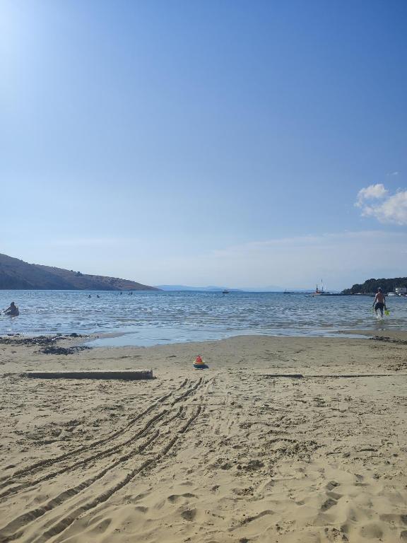 a beach with people walking in the water at Apartments Luka in Rab