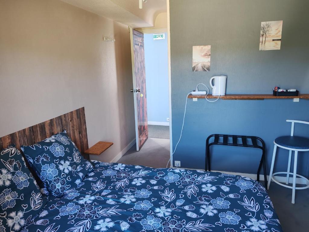 a bedroom with a bed with blue sheets and a stool at L'Etape in Pont-d'Ouilly