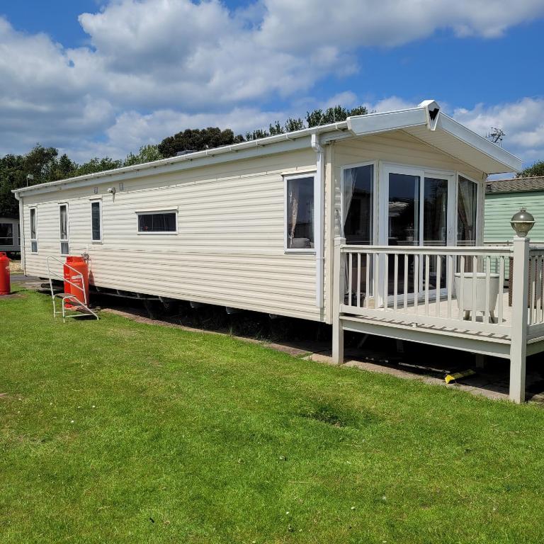 a white mobile home with a porch on a lawn at 125 Maple Lake Southview Caravan Park in Winthorpe