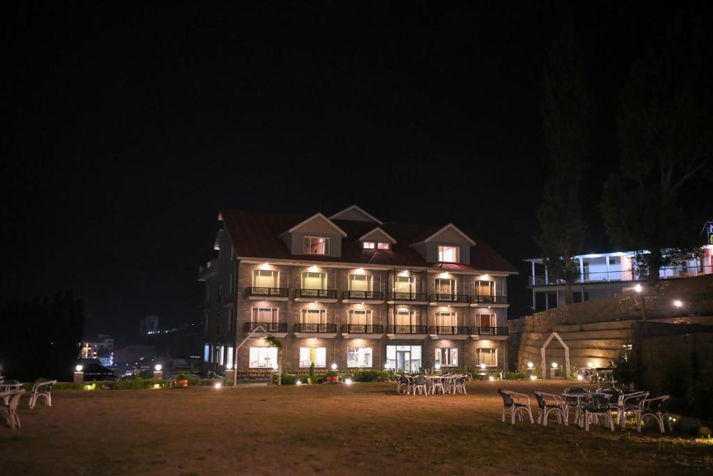 a large building with tables and chairs at night at Hotel Demanchi Kalam in Kārandūkai