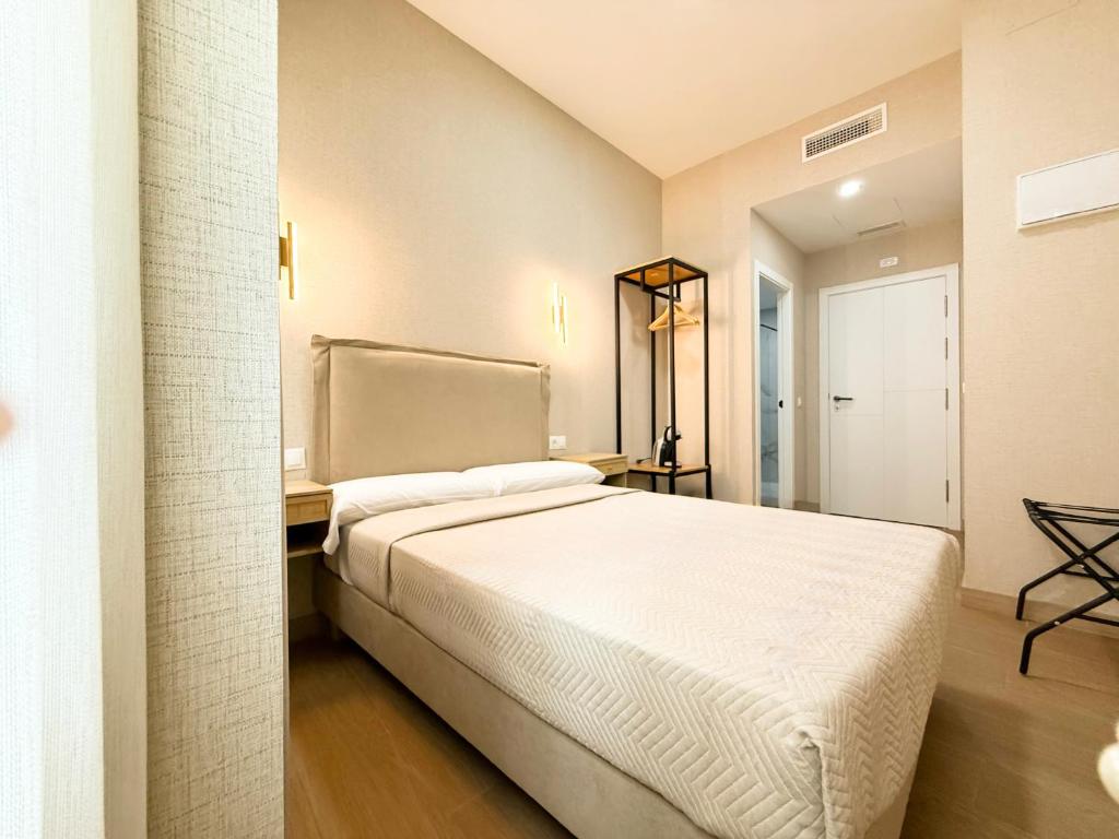Un dormitorio con una gran cama blanca en una habitación. en Boutique Palacio Centro, en Alicante