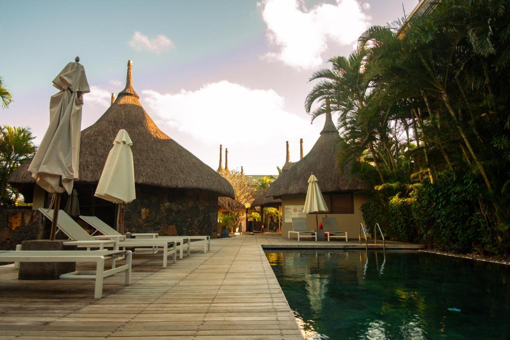 un resort con piscina, sedie e ombrelloni di Appartement de Luxe au Domaine des Alizées Club & Spa, Grand Baie a Grand Baie