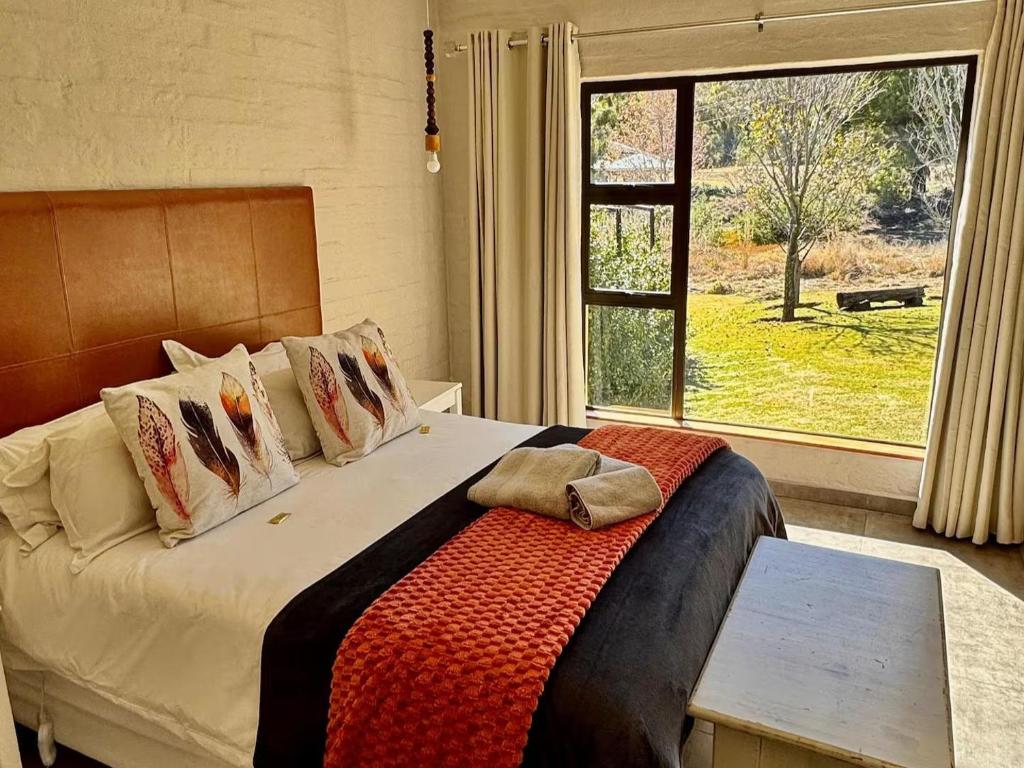 una camera da letto con un letto con una grande finestra di Muirfield Cottages a Clarens