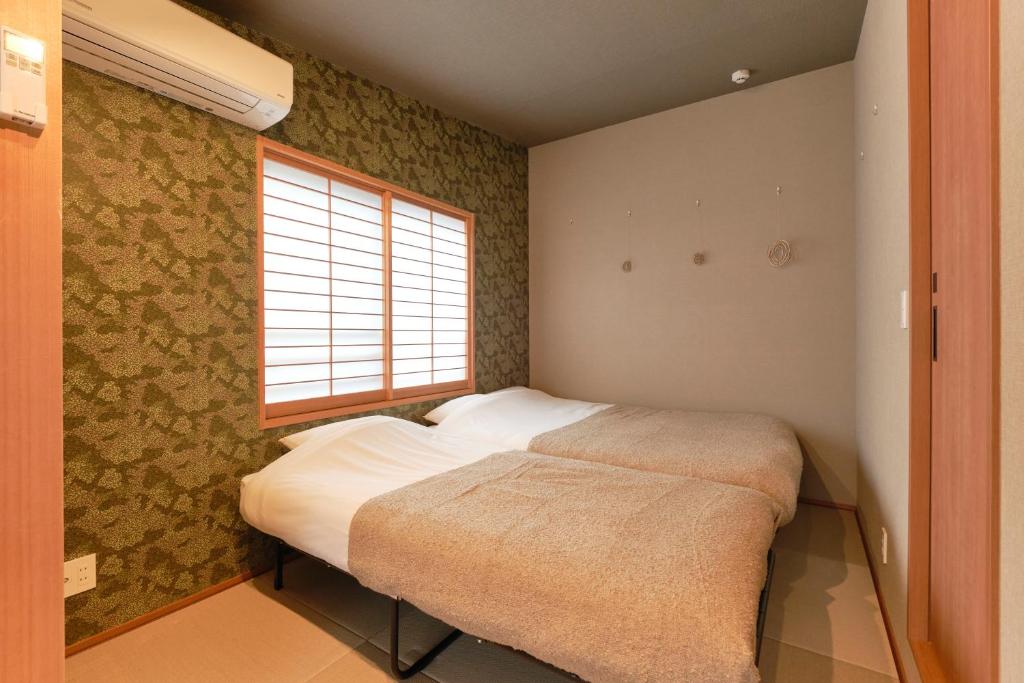 a small bed in a room with a window at Asagaya House by Tranova in Tokyo