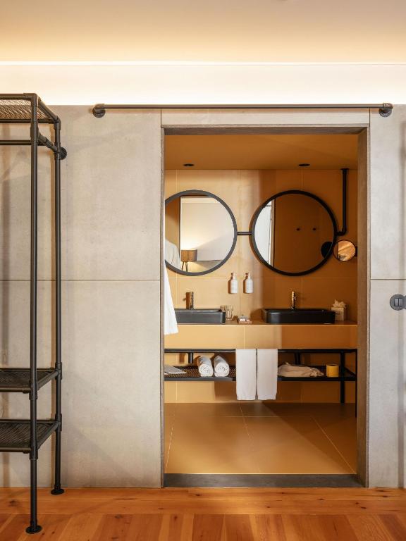 A warm-toned bathroom features twin round mirrors and twin basins.