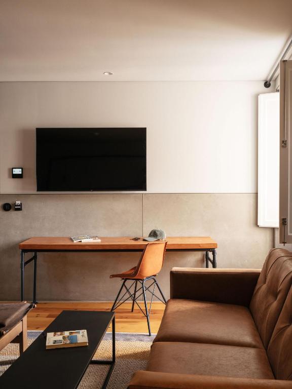 A wall-length desk beneath a television, paired with a leather sofa and chair.
