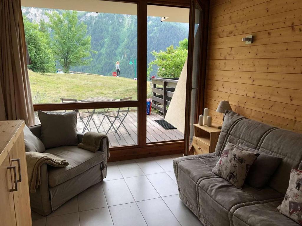 Una sala de estar con un sofá y una puerta corrediza de vidrio. en Le Parc03, en Peisey-Nancroix