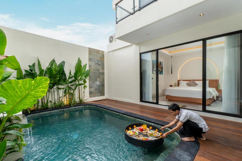 a man in a villa with a bowl of food in a pool at Nidya Villa Canggu in Canggu