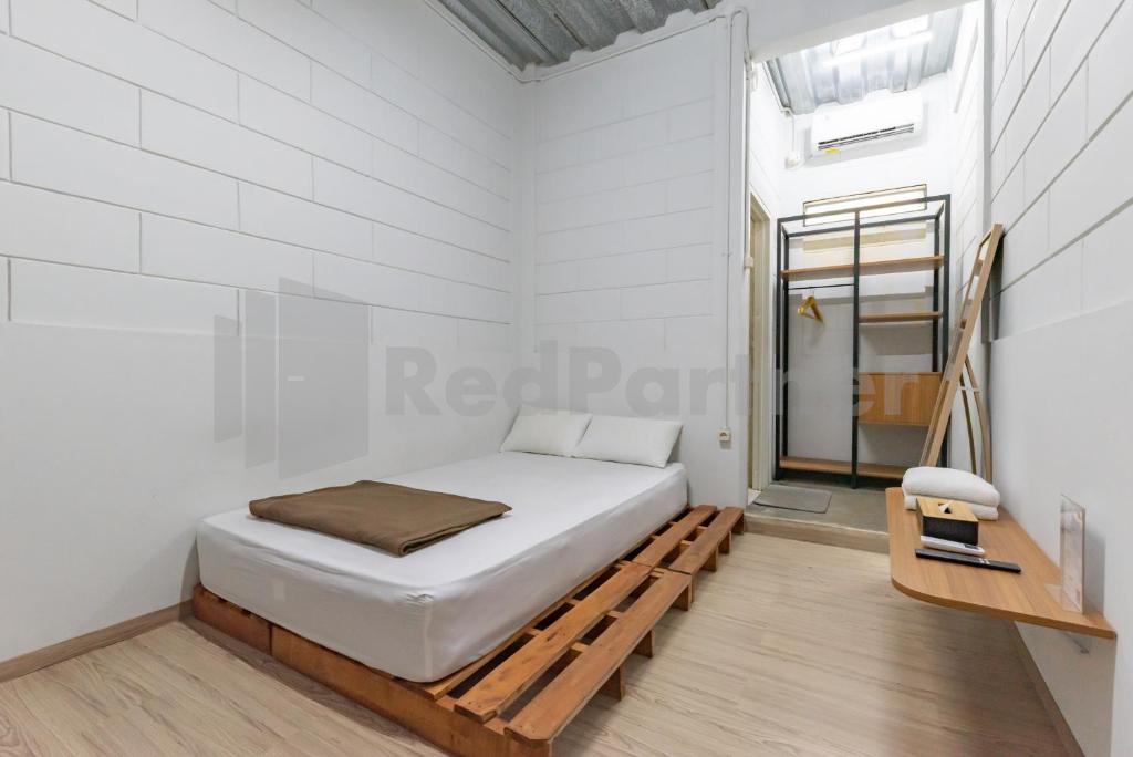 Un dormitorio blanco con una cama y una mesa. en Manta Living Bandung RedPartner, en Bandung