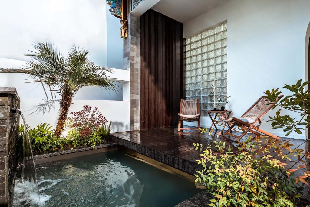 a swimming pool in the middle of a garden with two chairs at 山也云也大理古城南门店 in Dali Ancient Town