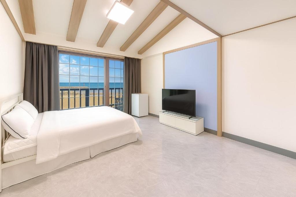 a bedroom with a bed and a flat screen tv at Taean Hagampo Rendezvous pension in Taean