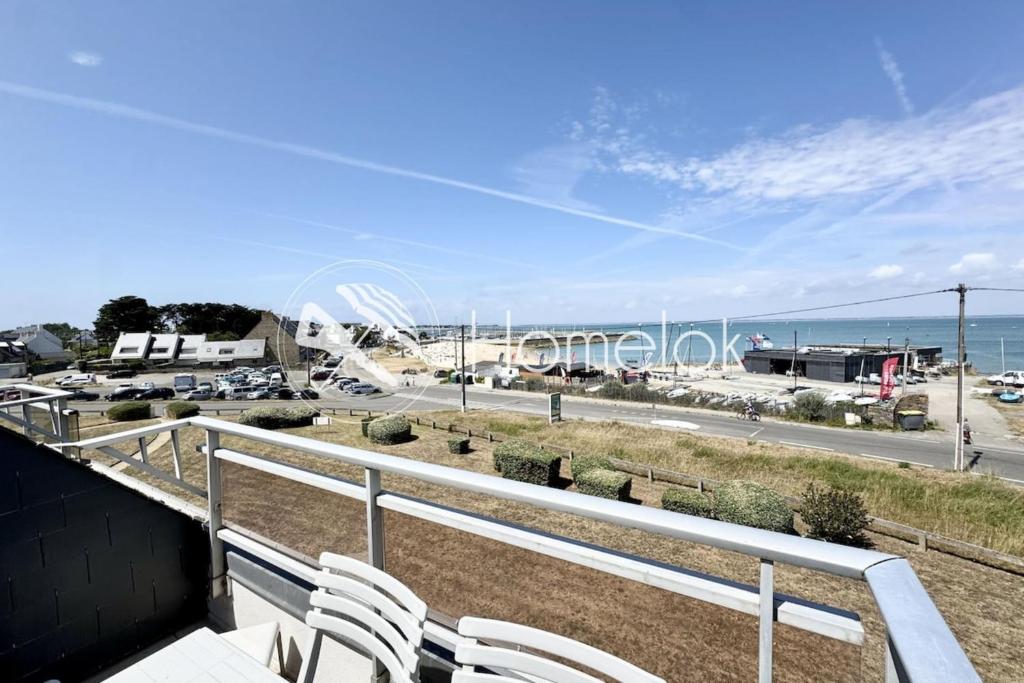 a balcony with white chairs and a view of a beach at Duplex plein charme Face mer & déco moderne in Quiberon