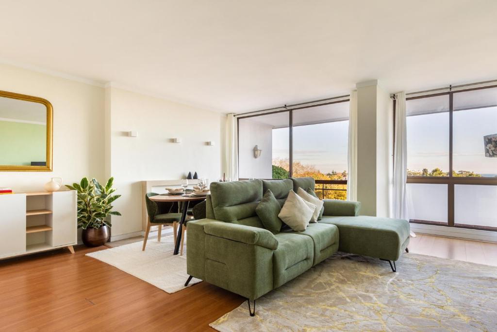 a living room with a green couch and a table at 3BR Apt w Balcony and Sea View in Cascais