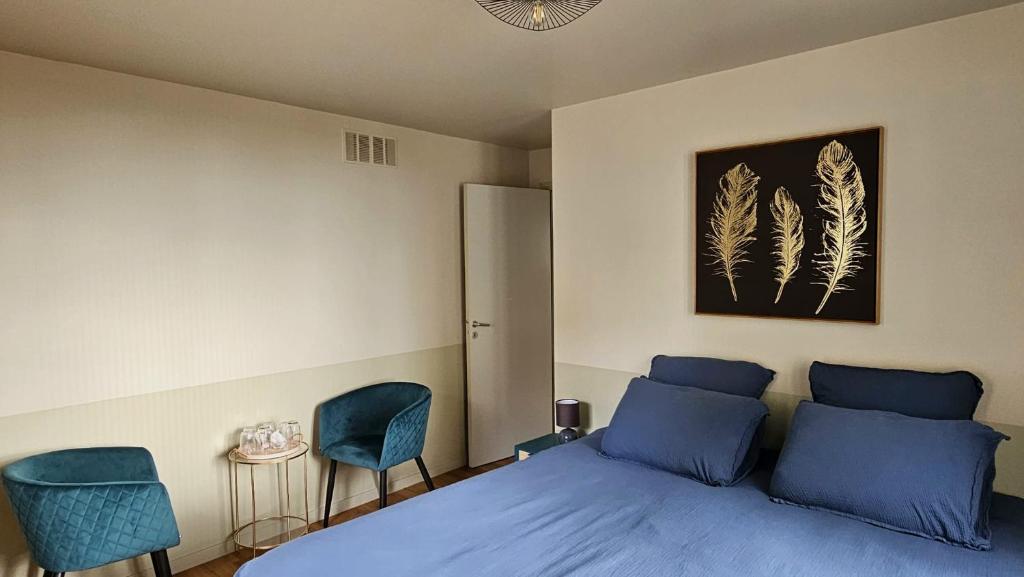 a bedroom with a blue bed and two chairs at Aux Tilleuls de Renaison in Renaison