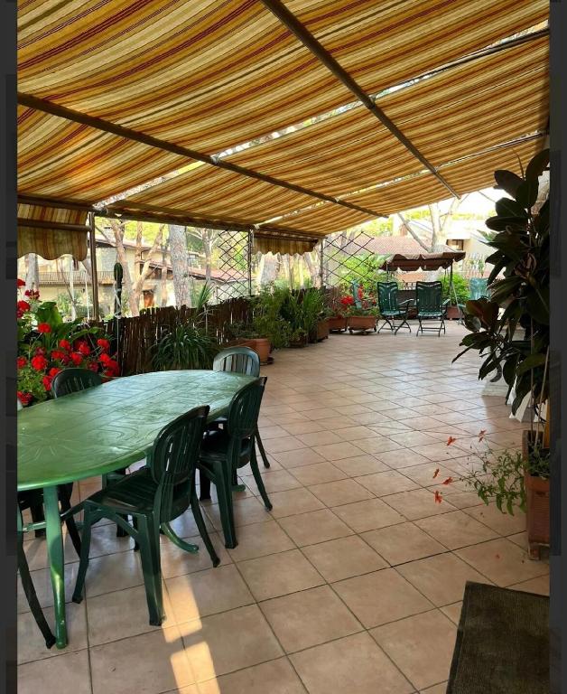 a patio with a green table and chairs under a tent at Puccini 200 mt dal mare con parking in Castiglione della Pescaia