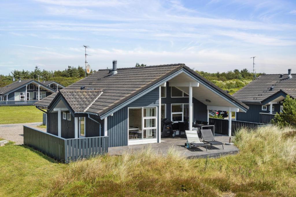 a blue house with a deck on the beach at Feriehus 1127 in Ringkøbing