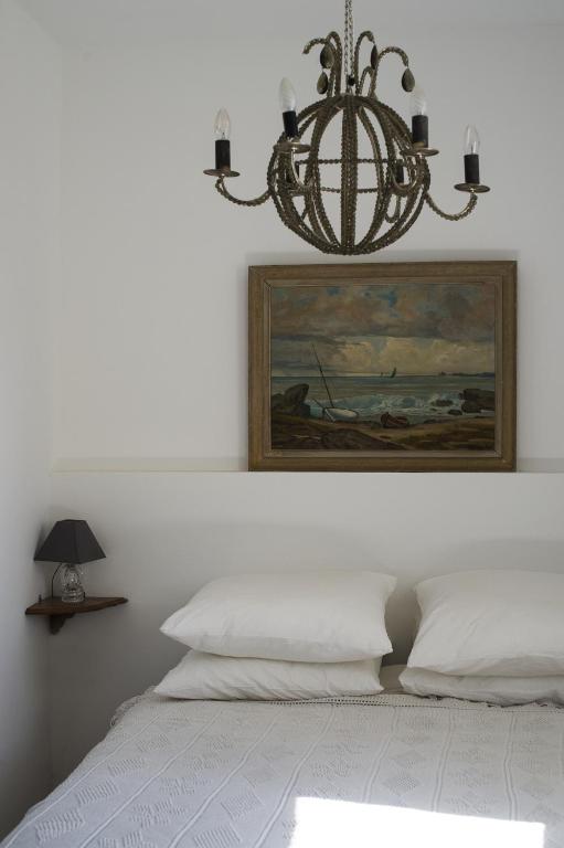 un lustre suspendu au-dessus d'un lit avec une peinture dans l'établissement Chambres Avec Vue, à Sète