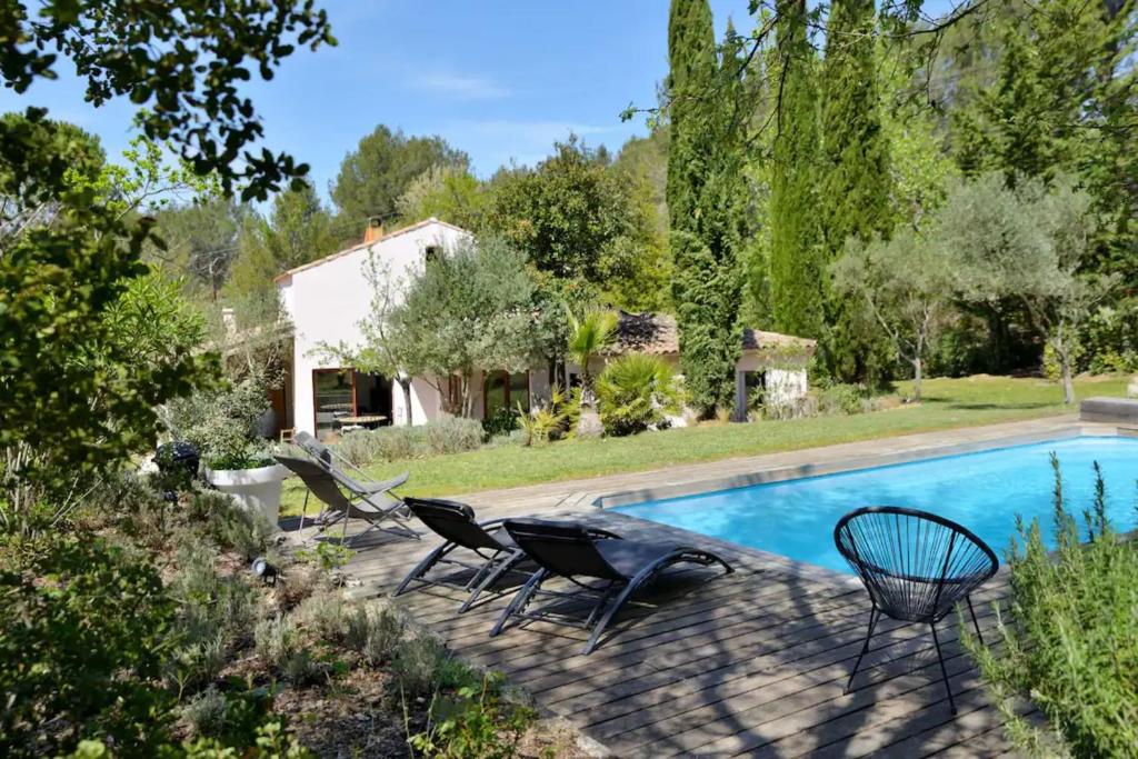 une piscine avec deux chaises et une maison dans l'établissement Family cottage with private pool, à Fuveau
