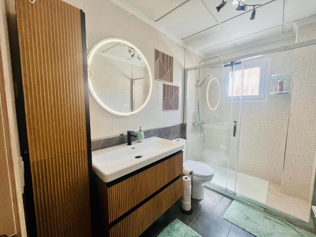 Un baño con lavabo, inodoro y espejo. en Casa La Paz, en Torrevieja